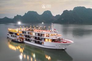 a cruise ship in the water with mountains in the background at Aqua of the Seas Cruise in Ha Long