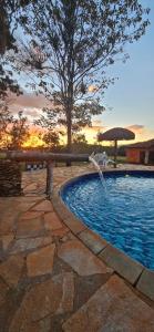 a swimming pool with a fountain and a tree at Recanto do Baru in Pirenópolis