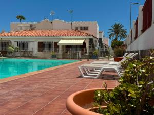 a swimming pool with lounge chairs next to a building at Parrot Cage - the Gay Villa in Playa del Ingles