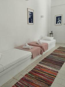 two beds in a white room with a rug at White Cat in Vromolithos