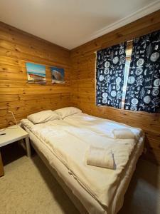 a bedroom with a bed with a wooden wall at Trolltunga byFjord in Odda