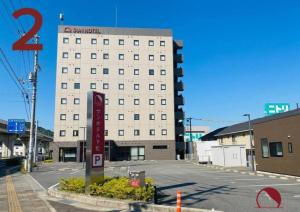 a large white building with a sign in a parking lot at Sun Hotel Kudamatsu in Hanaoka
