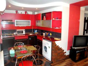 ヘルソンにあるMaxim Apartmentのキッチン(赤いキャビネット、テーブル、テレビ付)