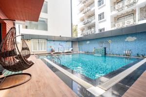 a large swimming pool with chairs and a swing at Trayee International in Digha