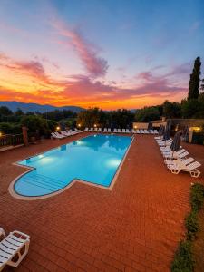 a pool with chairs and a sunset in the background at Agriturismo L'Antica Vigna in Randazzo