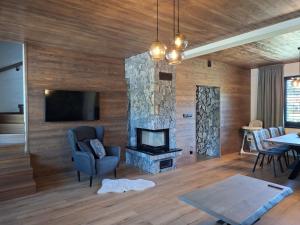 a living room with a stone fireplace and a tv at Chalet Johannes in Liptovský Ján