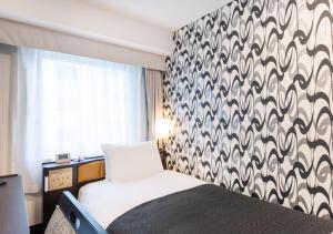 a bedroom with a bed with a black and white patterned wall at APA Hotel Kyoto Eki Horikawadori in Kyoto