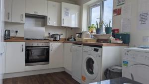 a kitchen with white cabinets and a washer and dryer at NG Property in Glasgow +20 photos