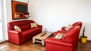 a living room with two red chairs and a table at Raíces in Puerto Pirámides