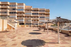 a patio with benches and an umbrella in front of a building at Bungalow Barlovento Playa in Arenales del Sol