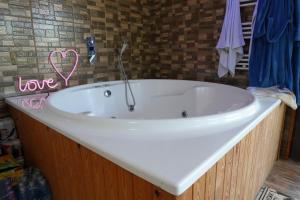 a white bath tub with a heart sign on the wall at SpaOk & Play in Mărgăriţi +38 photos