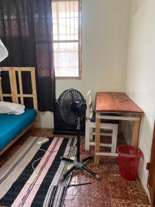 a room with a desk and a fan and a bed at Homestay in Wilkinson road in Freetown