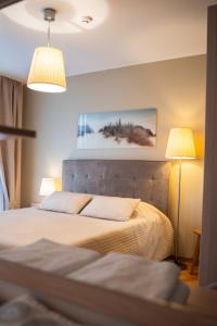 a bedroom with a large bed with two lamps at Naglio apartamentai Elija in Šventoji