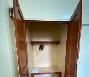 a closet with a wooden door and a shelf at Homestay in Wilkinson road in Freetown