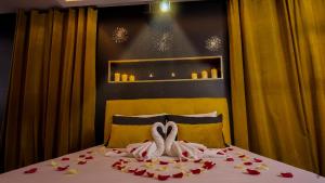 a bed with two swans towels and flowers on it at L'Écrin d'Or - Spa - Cinéma privé in Saumur +10 photos