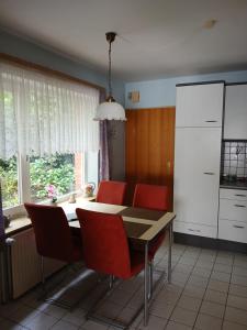 a kitchen with a dining room table and red chairs at Haus am Kirschbaum in Belum