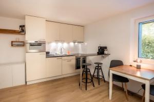 a kitchen with white cabinets and a table and chairs at Studio Omis in Zermatt