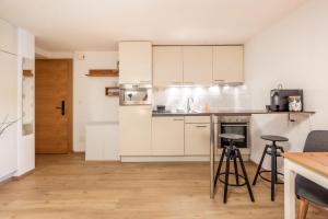 a kitchen with white cabinets and bar stools at Studio Omis in Zermatt