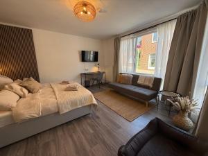 a bedroom with a bed and a couch and a window at Urban Nest Burg - Design Apartment mit Smart-TV, Self Check-in & Free Parking in Burg