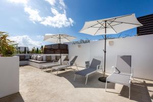 a patio with a couch and chairs and umbrellas at Paraíso maya apartaments in Playa del Carmen