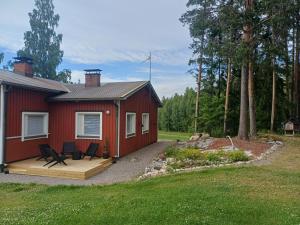 a red house with a deck and chairs in front of it at Loma Kallioniemi in Ähtäri
