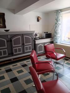 a living room with red chairs and a kitchen at Gîte du piémont in Mouzon