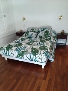 a bed with a green and white comforter on it at Gîte du piémont in Mouzon