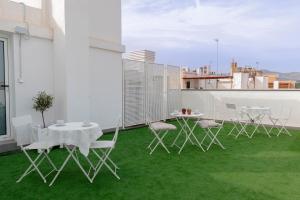 a balcony with white chairs and tables on a roof at La Inmaculada Alojamientos in Málaga +12 photos