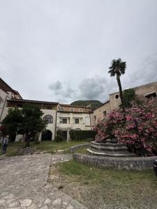 a building with a palm tree and flowers in a yard at Affittacamere Le Canossiane in Piedimonte dʼAlife