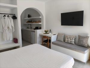 a white bedroom with a bed and a kitchen at Elena Studios & Apartments in Piso Livadi