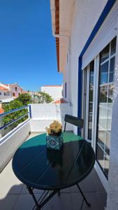 a glass table on a balcony with a chair at Soleil Bleu in Vila Nova de Milfontes