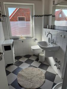 ein Badezimmer mit Waschbecken, Toilette und Fenster in der Unterkunft Hüs Sanskiin in Wittdün