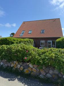 ein Haus mit rotem Dach und Steinmauer in der Unterkunft Hüs Sanskiin in Wittdün