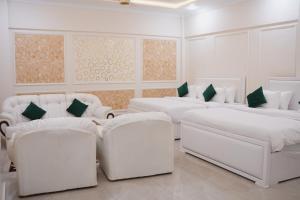 a white room with two beds and two chairs at Pc Inn Executive Class Hotel in Sukkur