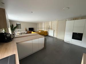 a kitchen with white cabinets and a living room at L'Aurore Céleste in Aywaille