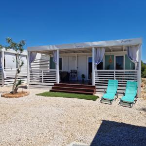 a house with two blue chairs and a porch at Mobile Homes Albatross in Pirovac