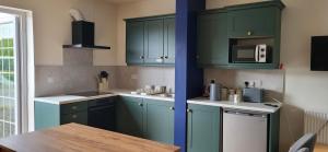 a kitchen with green cabinets and a wooden table at Ox Mountain View 3 Bed apartment in Foxford +3 photos