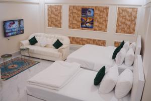 a white living room with two beds and a couch at Pc Inn Executive Class Hotel in Sukkur