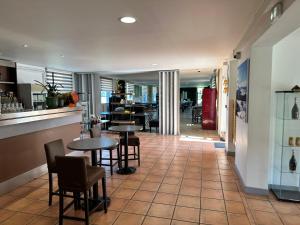 a restaurant with tables and chairs on a tiled floor at Logis Hôtel Restaurant Volcan Sancy in Nébouzat