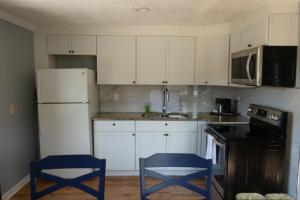 a kitchen with white cabinets and blue chairs in it at Aquastar Inn in Westerly