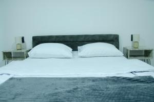 a bed with two pillows and two night stands at Apartman Crvenka stan na dan in Crvenka