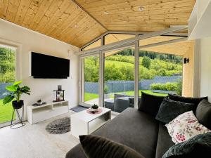 a living room with a couch and a flat screen tv at Voralpen Lodge - Ferienhaus mit Gym, Sauna & Hot Tub in Traisen