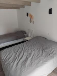 a bedroom with a large bed and a chair at Maisonnette meublée à la campagne in Ernée