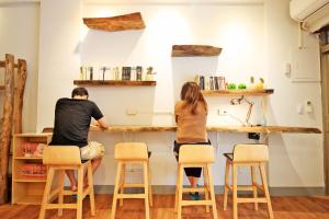 a man and woman sitting at a counter in a kitchen at Navel Orange Hostel in Taitung City