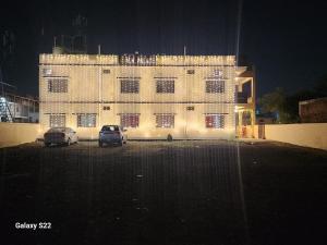 a large building with two cars parked in a parking lot at Hotel MNP in Jabalpur