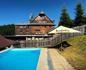 a house with a swimming pool and an umbrella at Horský hotel Portáš in Nový Hrozenkov