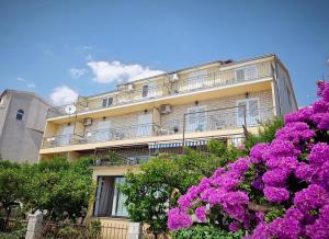 a building with purple flowers in front of it at Apartments Slaven in Podgora