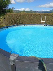 a large blue swimming pool with a chair next to it at Casa rústica O NOSO VAL in Mondariz