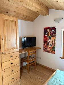 a bedroom with a desk with a television and a bed at Casa Seler - Appartamento verde in Predazzo