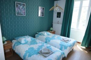 two beds in a room with green wallpaper at Sous La Treille in Saze